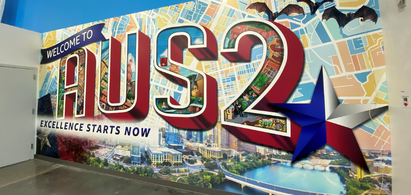 A large vinyl wall mural depicting the AUS2 warehouse name, tagline and artwork that reflects the community.